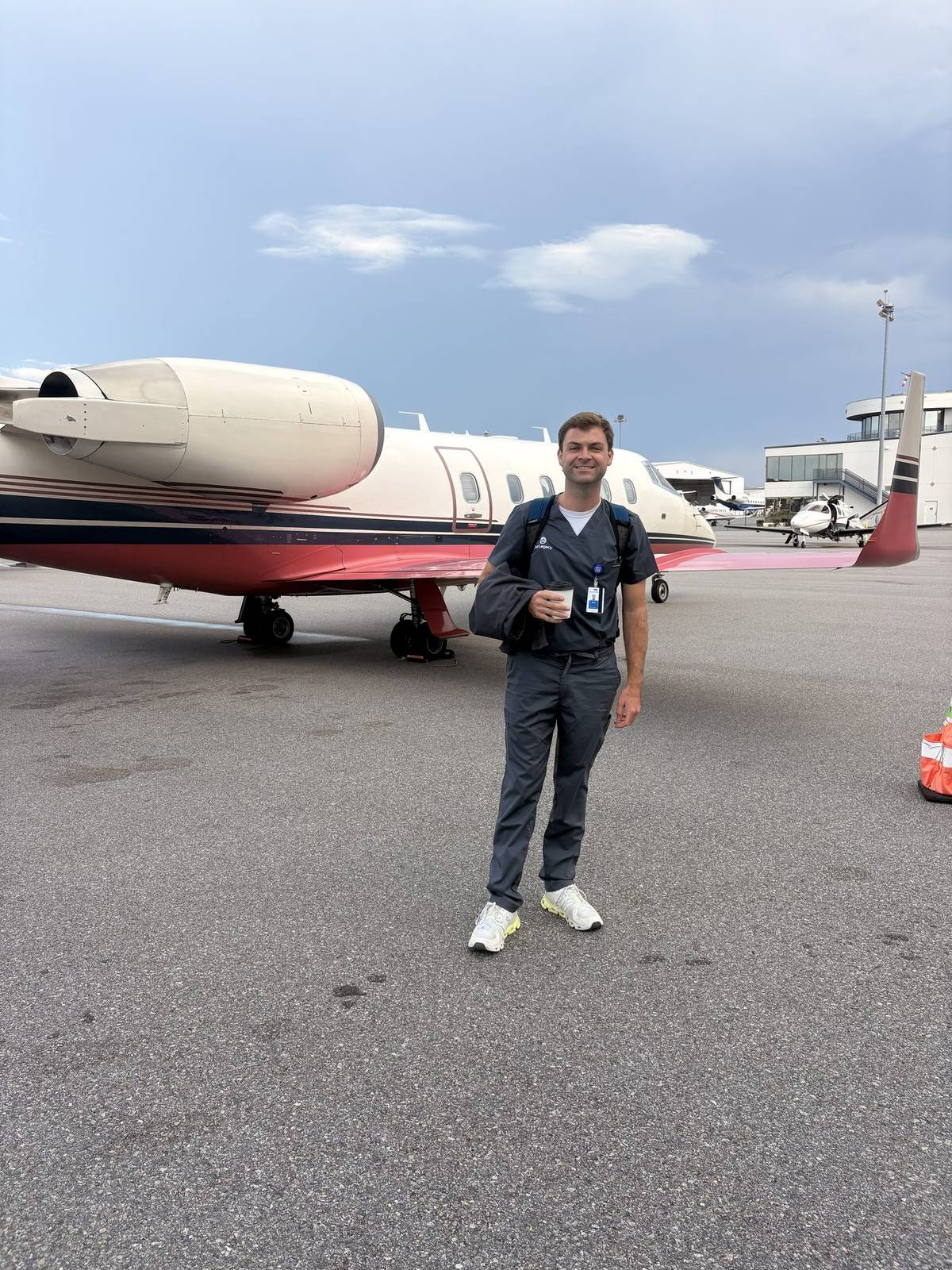 Sam Cornell in scrubs on an airport ramp beside a jet